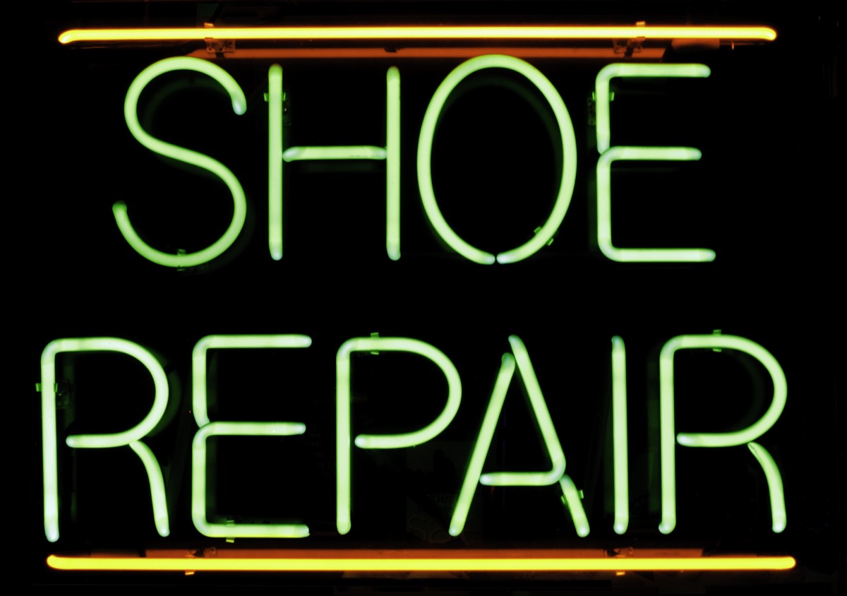 A computer repair shop storefront with a lit sign on a commercial street