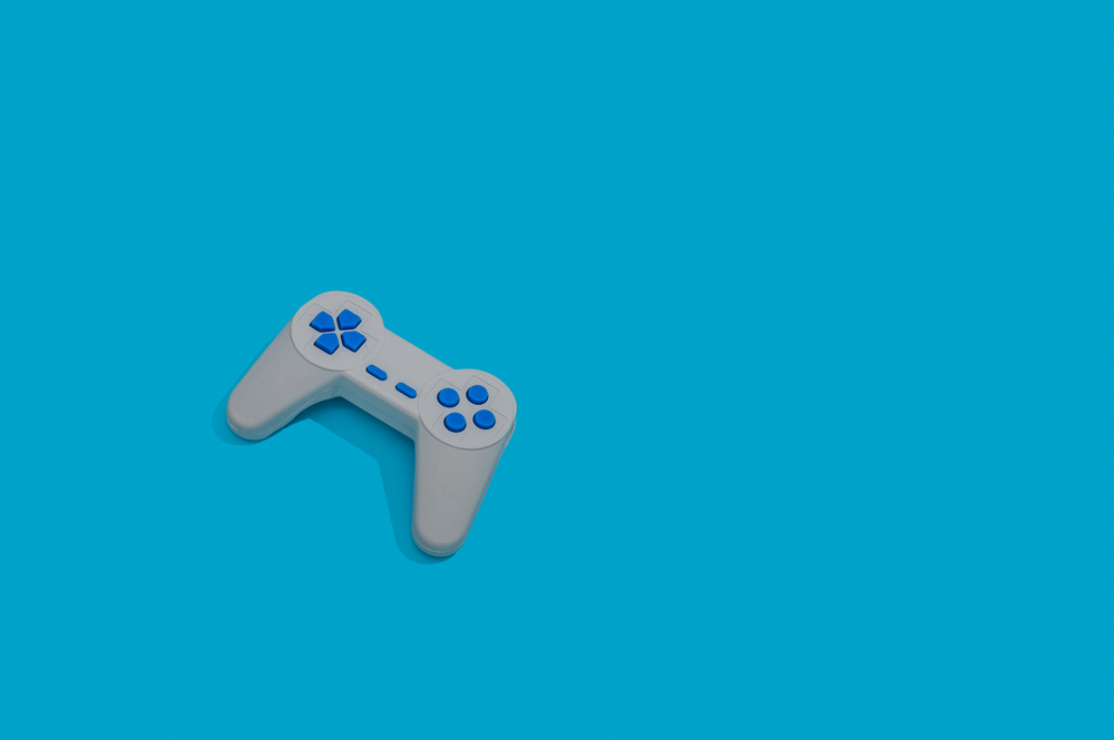 A video game controller resting on a screen showing a music rhythm game