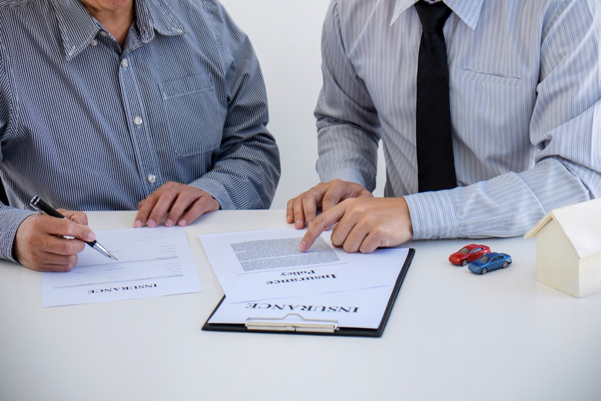 An insurance agent reviewing a printed client account file at a desk