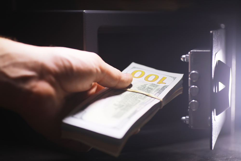 A wooden judge's gavel resting beside stacks of paper currency on a desk