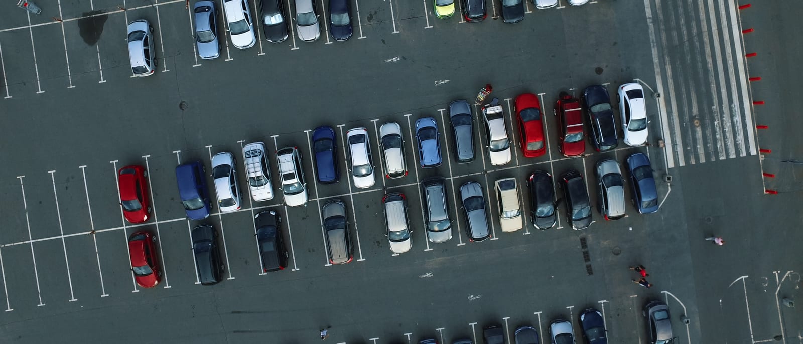 Rows of parked cars in an airport long-term parking lot at dusk