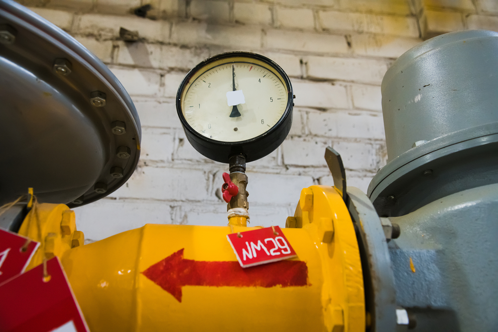 A network of steel pipes, valves, and pressure gauges at a petrochemical refinery