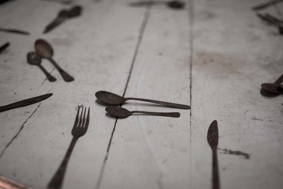 Ornate silver dinner forks and spoons arranged on a dark surface