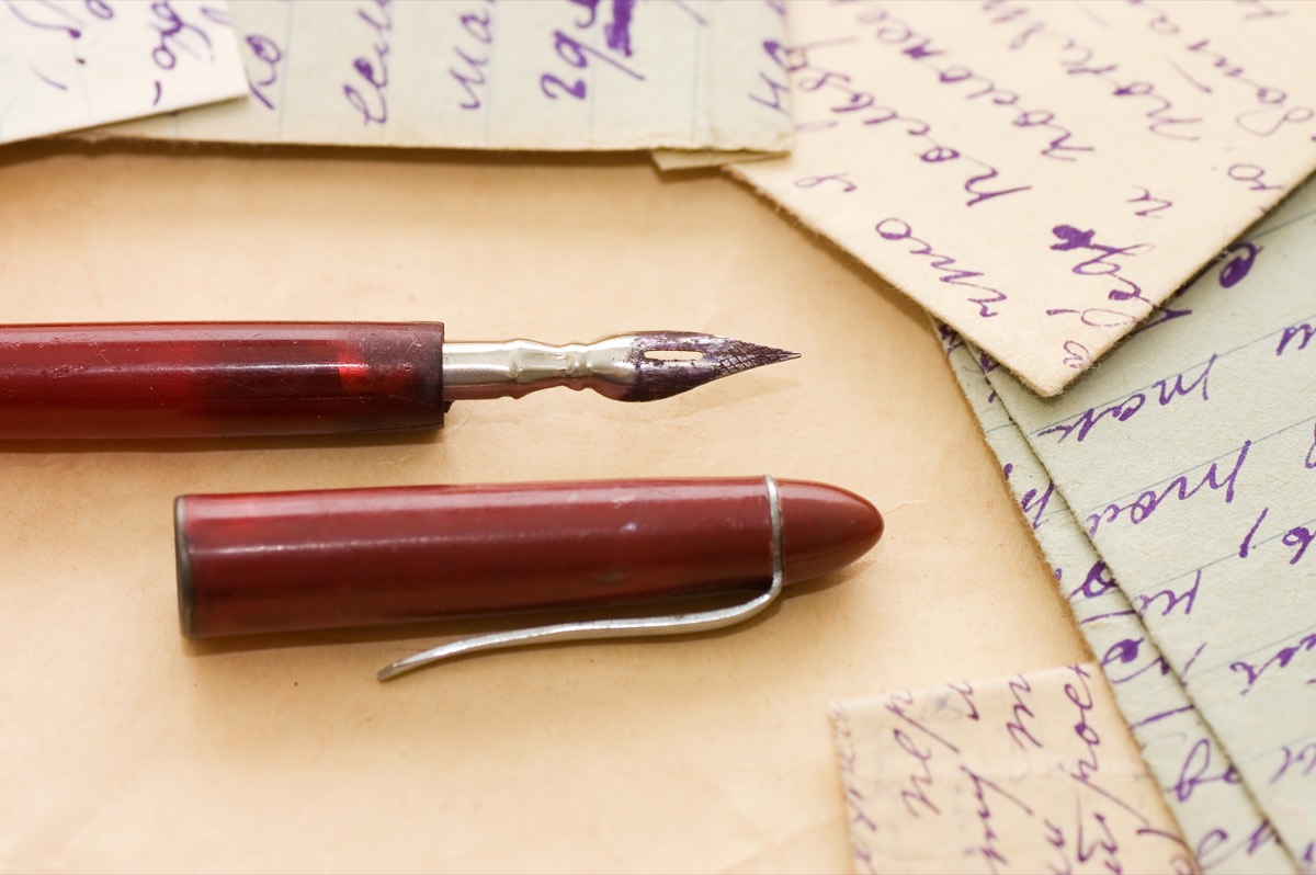 A stack of mid-century hardcover novels beside a fountain pen and a publishing contract