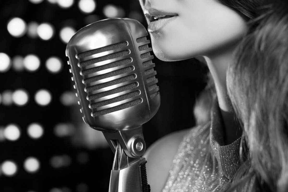 A vintage microphone on a stand under a spotlight on a dark stage