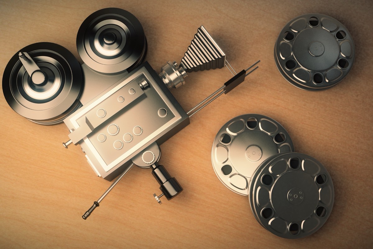 Vintage film reels and an old movie projector on a wooden surface