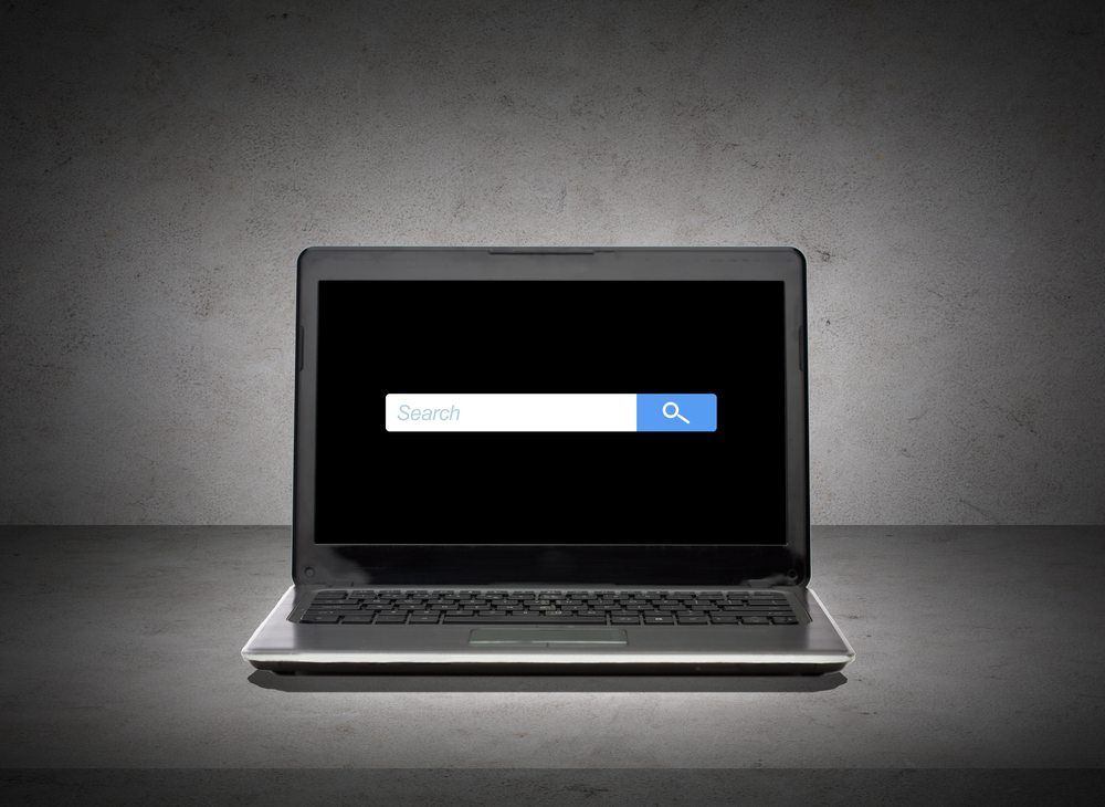 A search engine query box with sponsored results on a laptop screen