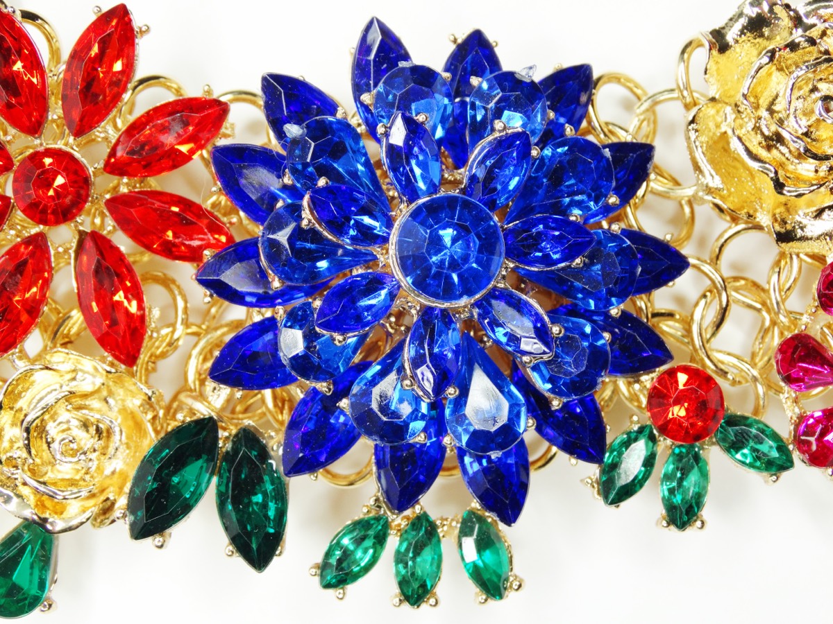 A gold bee-shaped brooch set with small gemstones displayed on a jeweler's velvet tray