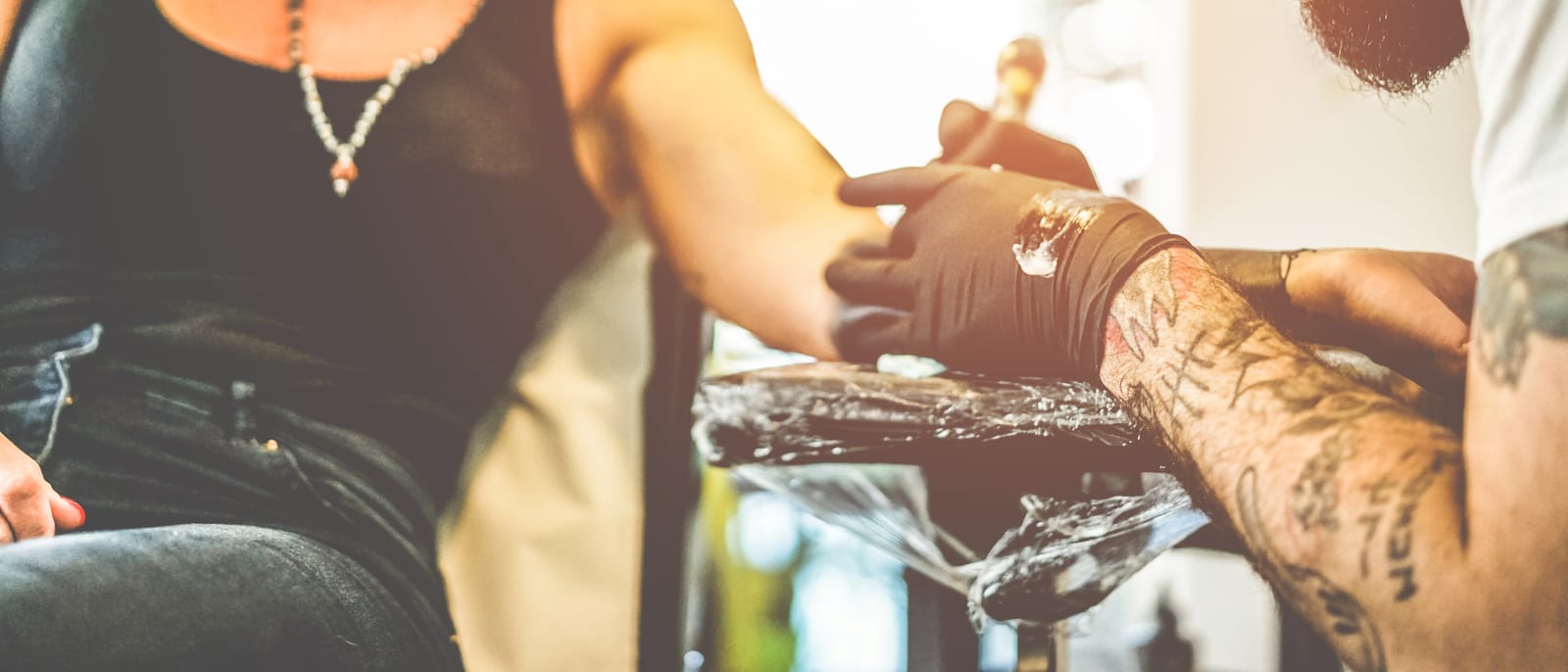 A tattoo artist working on a client's arm in a studio under bright light