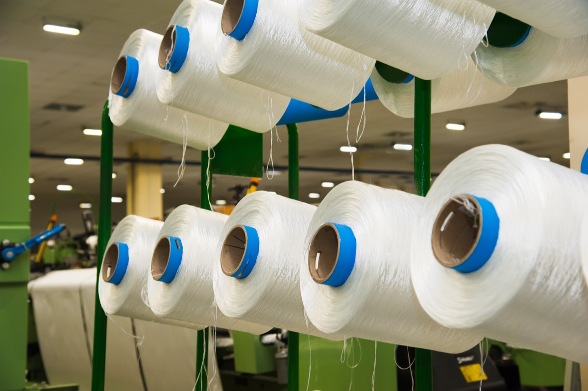 Rolls of wool knit fabric stacked in a textile mill warehouse