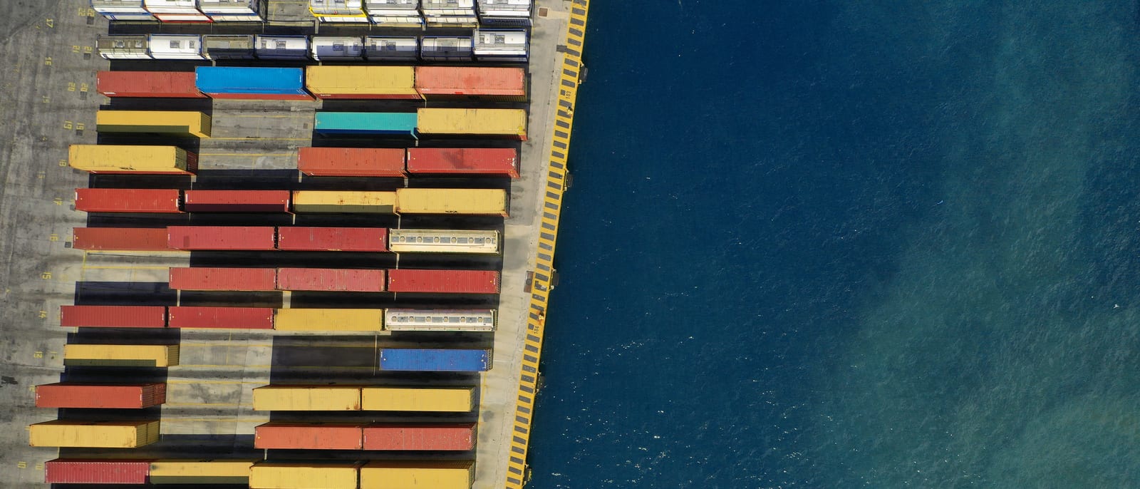 Stacks of shipping containers at an international port at dusk