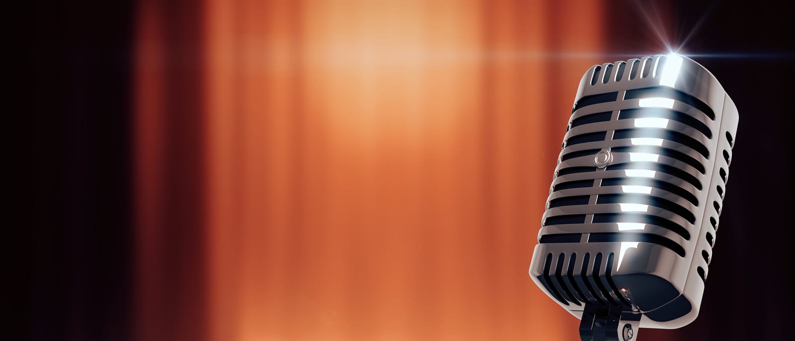A vintage broadcast microphone beside studio headphones on a mixing console under warm light