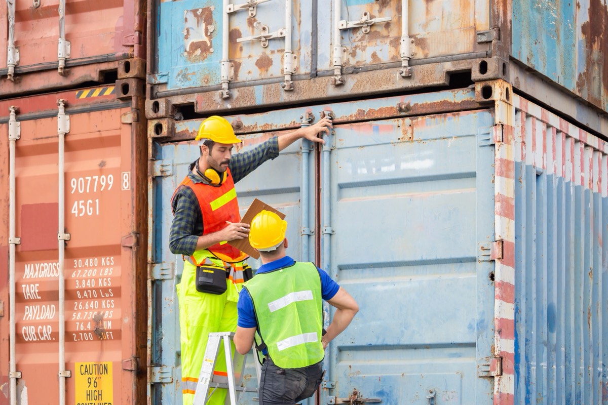 Cargo containers stacked at a port with a customs inspection area