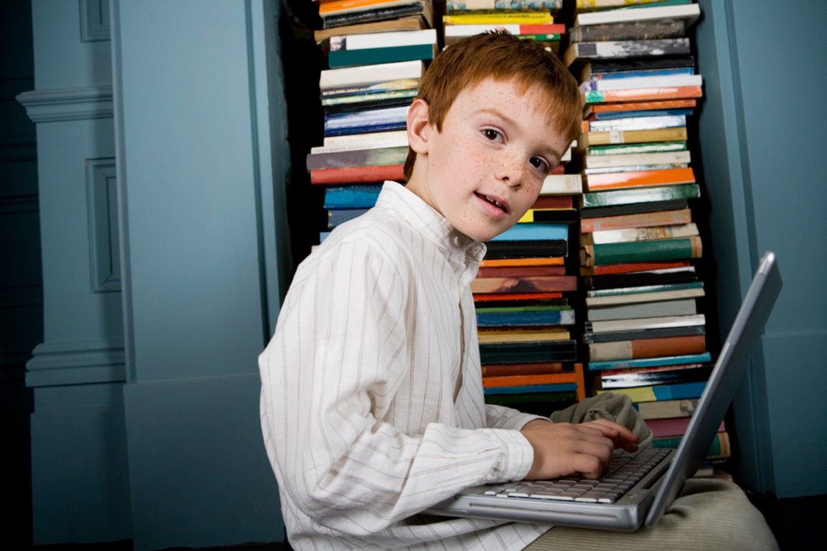 A stack of hardcover novels beside a laptop displaying a text chat interface