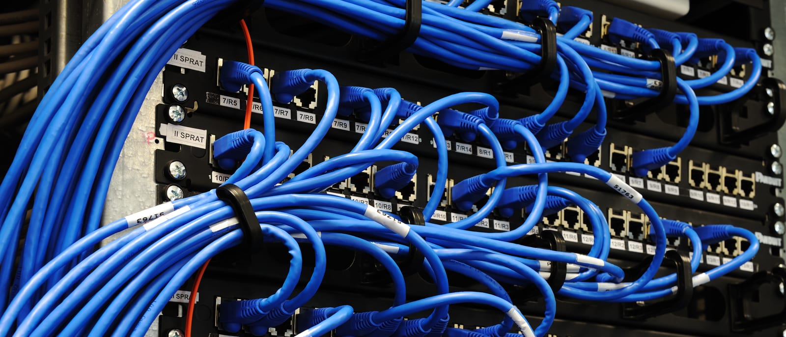 Rows of network servers with glowing fiber-optic cables in a data center