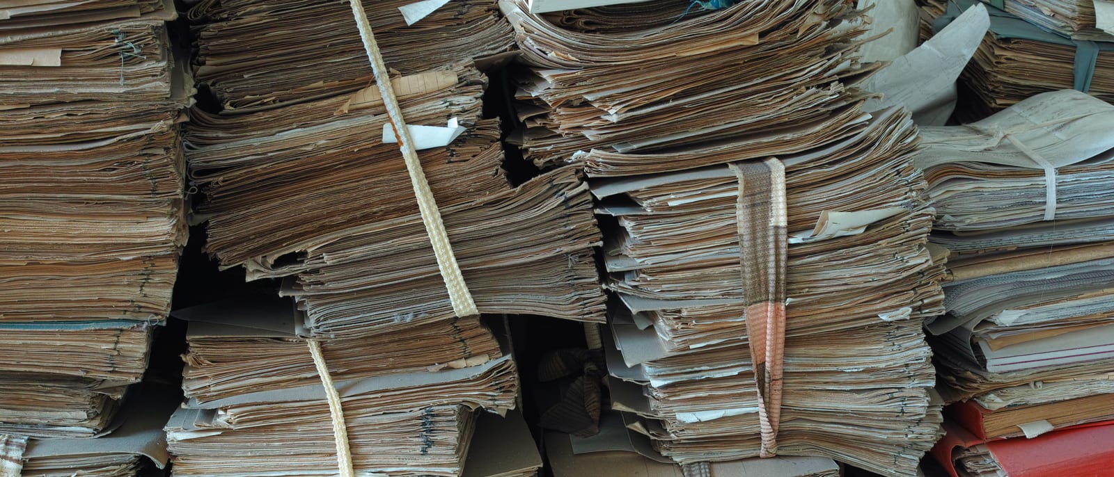 Stacks of technical binders and documents in a dim basement storage area