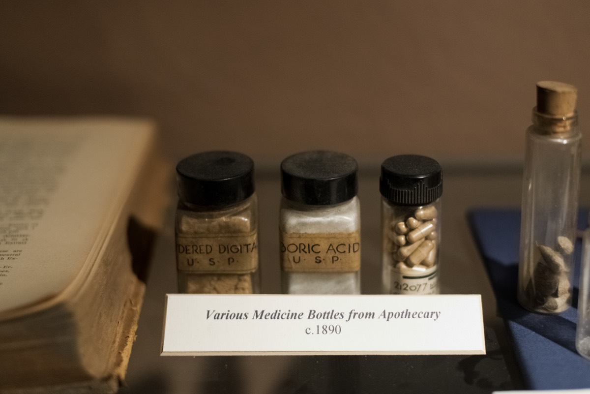 An antique amber glass medicine bottle beside a handwritten formula on aged paper
