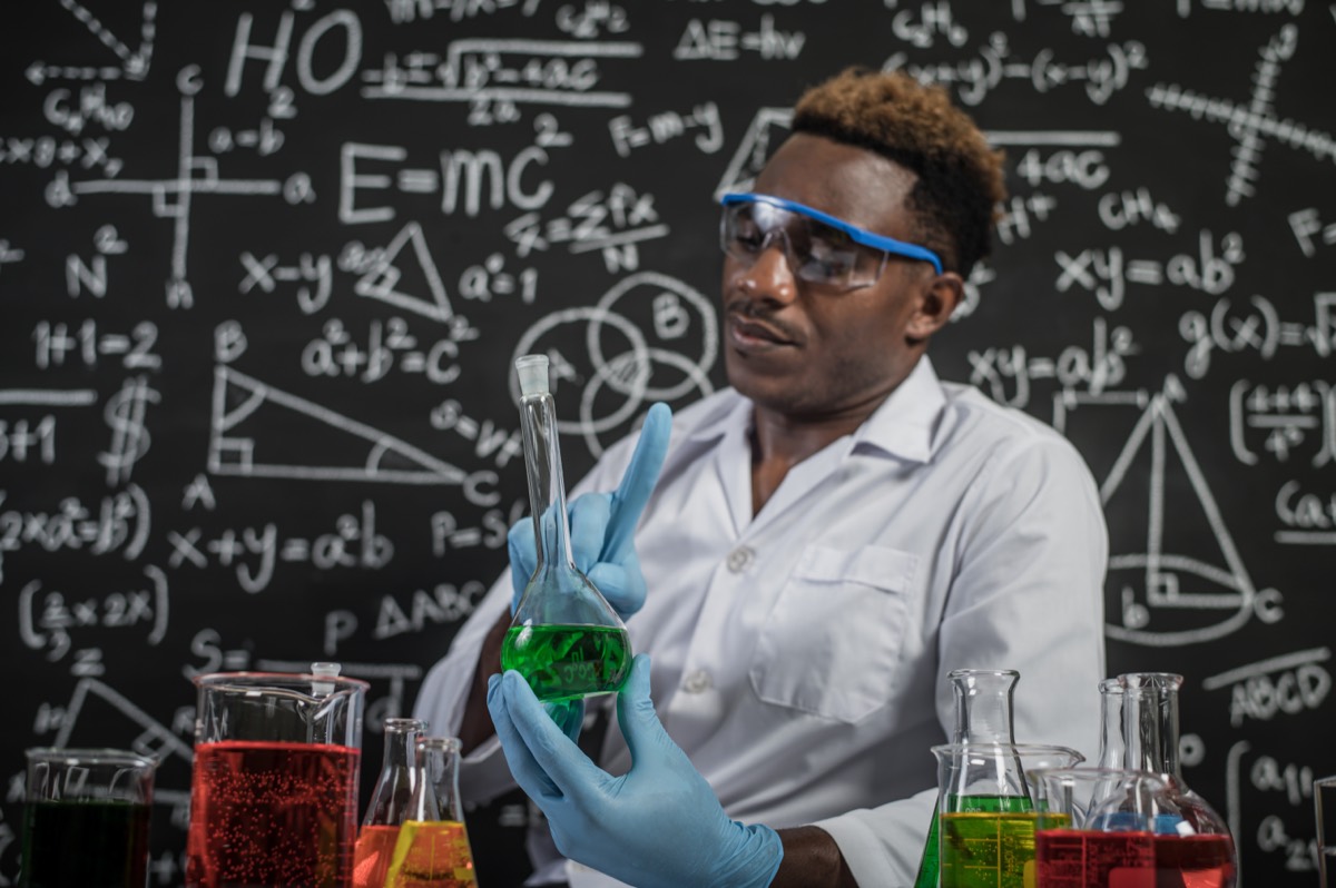 A chemist in a laboratory mixing cleaning solutions in glass beakers