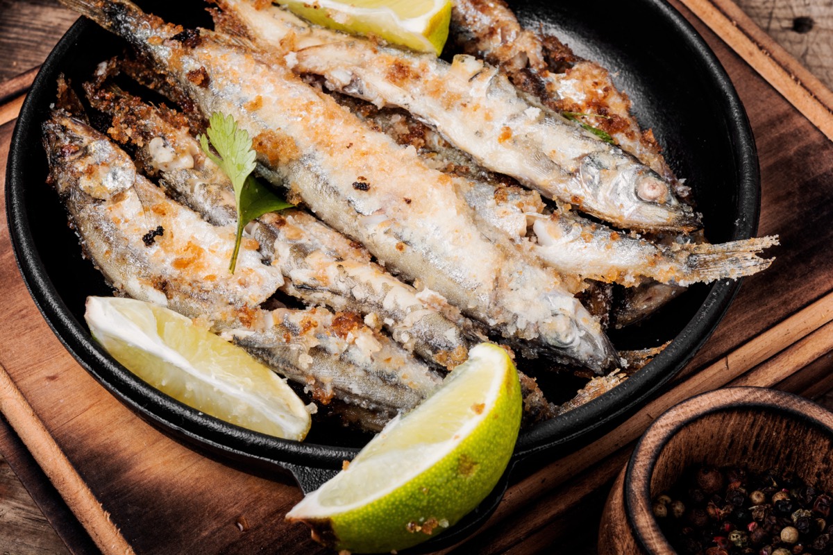 Golden fried fish fillets cooking in a cast iron skillet with cornmeal batter